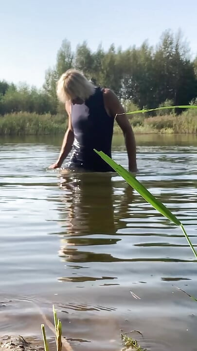 Trans djevojka pliva u jezeru u plavoj sportskoj haljini. Wetllok trans djevojka mokra.