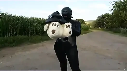 Fetish slave in latex walks and sucks a dildo on the grass
