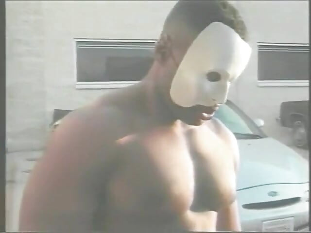 Muscular Stranger in White Superhero Mask Drills Ebony Chick on the Parking of Shopping Mall
