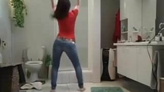 Une allumeuse brunette bandante en jeans danse