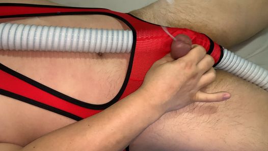 Homem gordo vestindo lingerie vermelha esfregando um pênis pequeno em uma mangueira de vácuo e gozando