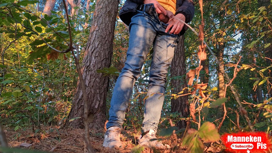 Tío meando en el bosque bajo un árbol