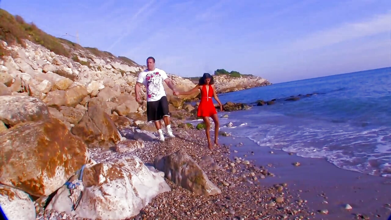 Sexy babe in red dress and muscle guy on the beach