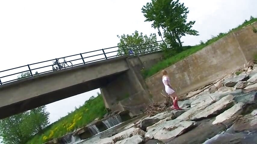 Blonde pissing outside in a river