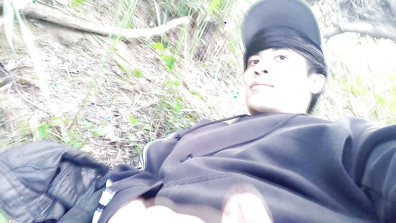 The cute gay twink jerking off his cock, pulled through his fly while outdoors, is Jon Arteen