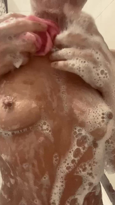 ung tøs spytter på sine skummende bryster i brusebadet
