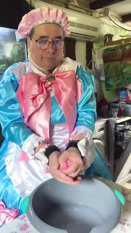 In un vestito da cameriera blu con fiocchi rosa per fare il bucato.