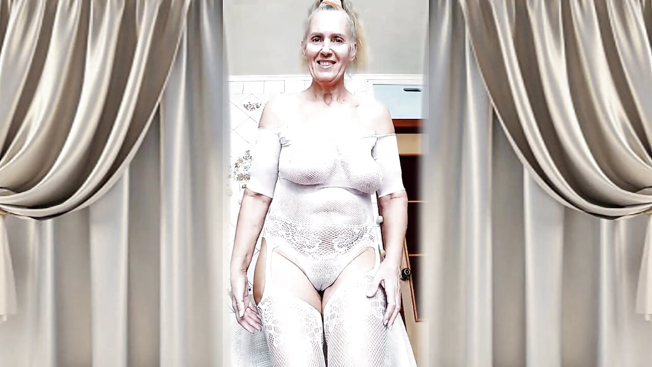 Hot housewife Lukerya flirts in an open transparent white jumpsuit in the kitchen.