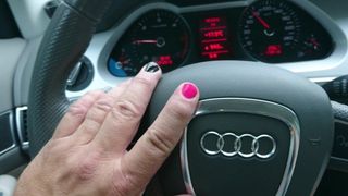 Crossdressed in glänzenden Nylons, Kleid und High Heels beim Auto fahren.