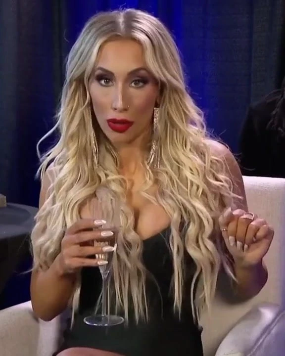 WWE - Carmella sotting in a low-cut black dress