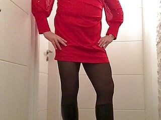 Nicki-travestie dans une mini-robe rouge sexy, collants et bottes