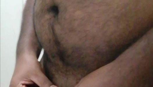 A horny black Asian man pissing and filling a bottle with his urine