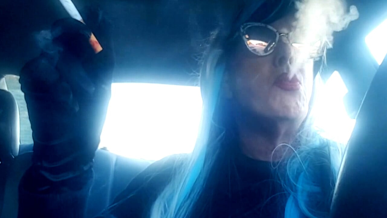 MATURE CD SMOKING & DRIVING WITH A MB100 CIGARETTE IN HER GLOVED HAND