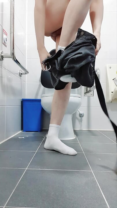 Süßer junge pinkelt auf seinen eigenen körper, während er nackt in der toilette ist