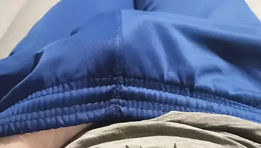 Facet w niebieskich spodniach dresowych pociera wybrzuszenie