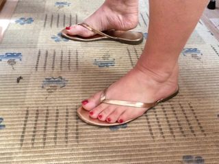 Sexy feet with red toenails and gold thong sandals