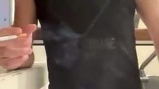 Un mec sexy fume en échangeant sa grosse bite