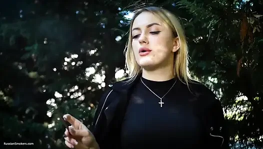 Heiße blondine raucht zwei schwarze zigaretten in der natur