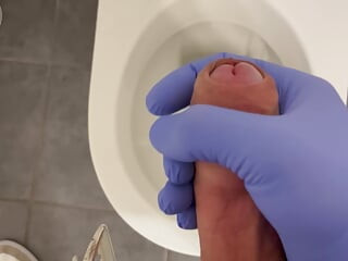 Médico masturbándose en un baño con guantes de látex