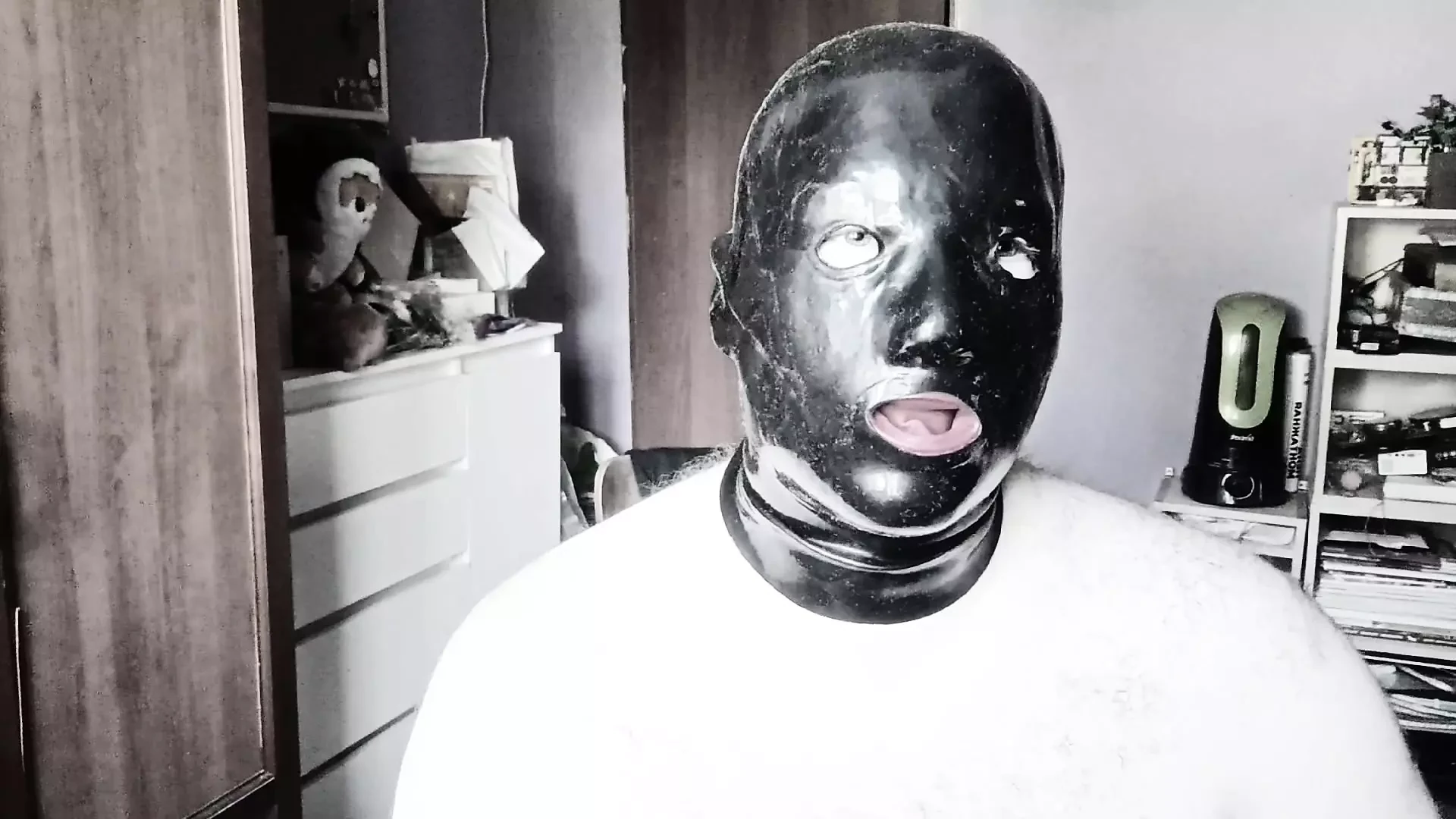 A guy in a latex mask with tubes for his nose jerks off and cums