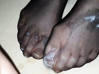 Calzino di nylon nero sulle unghie dei piedi francesi della moglie in dettaglio coperto da un grande carico di sperma