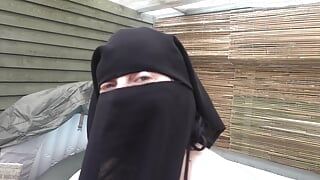 Sexy vrouw met grote borsten stript in niqab en stringbikini