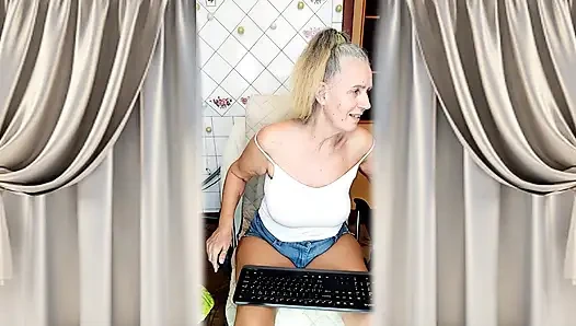 Cheerful housewife Lukerya flirts in the kitchen in tight denim shorts.