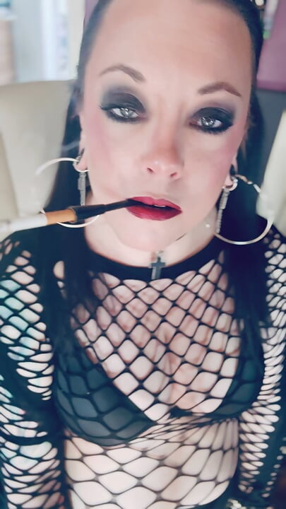 Gótica menina Tina Snua em tranças fuma um cigarro em um suporte e acendendo com partidas