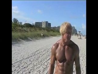 Um cara mais velho mostra um grande pau branco para uma praia de nudismo