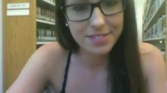 Doce garota com óculos mastrubte na biblioteca