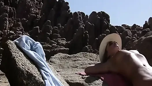 She Lies Naked on the Beach While He Watches Her