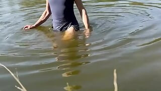 Trans djevojka pliva u jezeru u plavoj sportskoj haljini. Wetllok trans djevojka mokra.