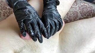 Ręczna robota w czarnych nylonowych rękawiczkach i footjob w czarnych pończochach seksownej dziewczyny