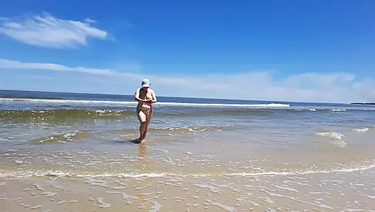 Amateur filming. A nudist plays with waves on the ocean shore.