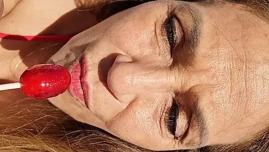 Melissa Johnson sucks and licks a cherry lollipop on the .beach