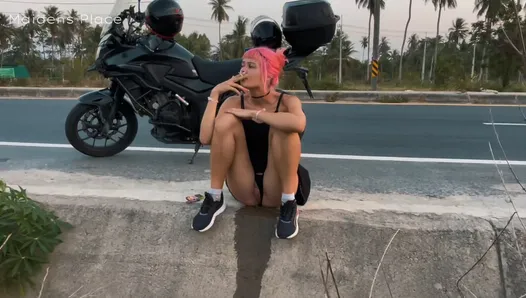 Dziewczyna z motocykla sika na poboczu drogi