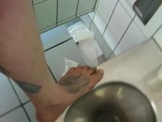 Barfuß auf einer dreckigen öffentlichen Toilette und etwas Pisse klopfen