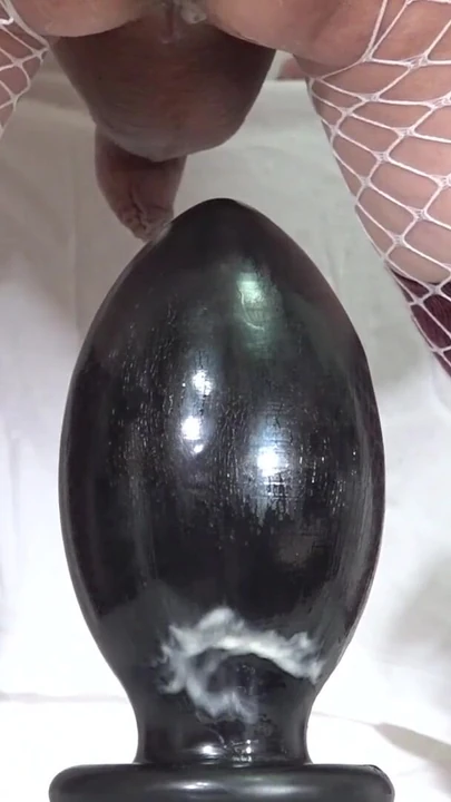 Iconic moment from "White Fishnet Sissy #14 - Riding a huge 95mm anal plug placed on a chair -"