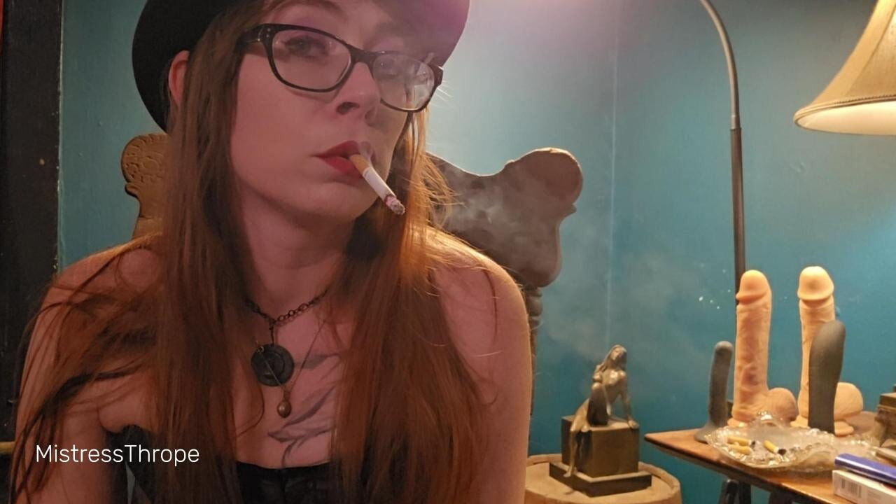 Smoking while wearing a purple corset, gloves, and a hat