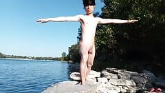 Ragazzo gay fa yoga nudo fuori su una spiaggia rocciosa, con i gay che passano e guardarlo. Ragazzo asiatico nudo che fa yoga all'aperto