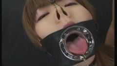 Japanerin lutscht mit einem großen Knebel mit offenem Mund