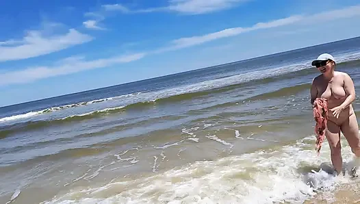 Rekaman seks amatir. Seorang nudis bermain dengan ombak di pantai laut.