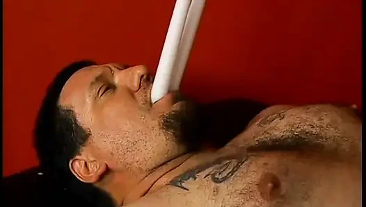 Latex-clad hottie torments a hairy guy with tats