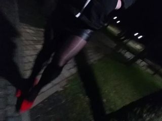 Crossdresser che cammina nel parco pubblico con i tacchi