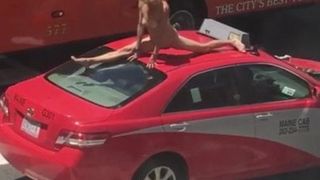 Mujer bailando en un auto en una calle concurrida