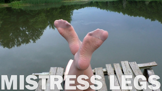 Maîtresse pieds en collants couleur chair sur le lac de la forêt