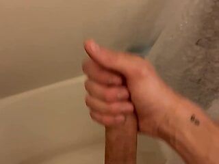 Un jeune minet mince caresse une grosse bite, squirte sous la douche.