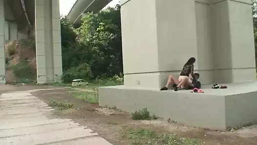 Lleva a una joven puta a follar debajo de un puente en un parque público