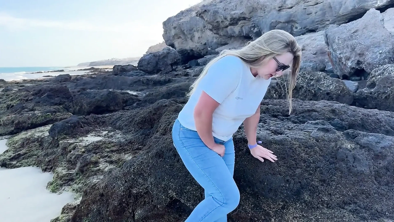 在海滩上穿着紧身牛仔裤撒尿