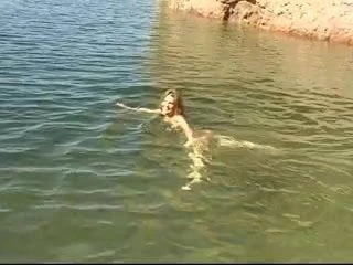 Cute young brunette strips by the water and goes skinny dipping